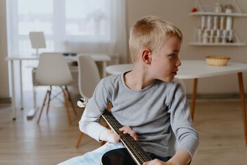 Mother and son playing guitar together, family love. The child wears a hearing aid, highlighting...
