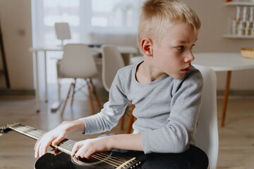 Mother and son playing guitar together, family love. The child wears a hearing aid, highlighting...