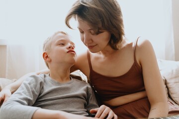 Mother and son playing guitar together, family love. The child wears a hearing aid, highlighting...