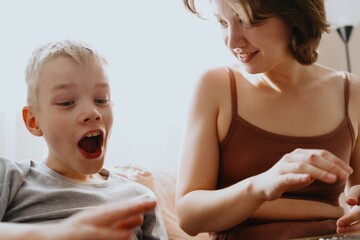 Mother and son playing guitar together, family love. The child wears a hearing aid, highlighting...