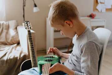 Mother and son playing guitar together, family love. The child wears a hearing aid, highlighting...