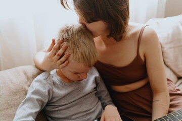Mother and son playing guitar together, family love. The child wears a hearing aid, highlighting inclusivity and the universal language of music. Authentic, unedited photo captures emotions