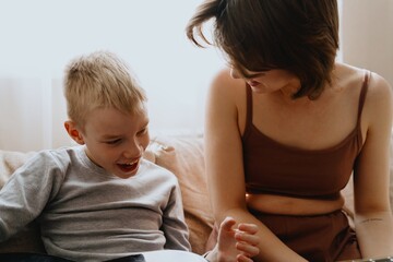 Mother and son playing guitar together, family love. The child wears a hearing aid, highlighting...