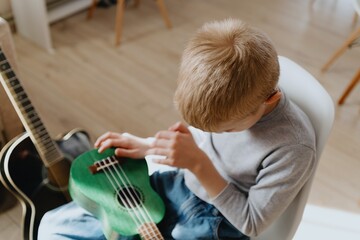 Mother and son playing guitar together, family love. The child wears a hearing aid, highlighting...