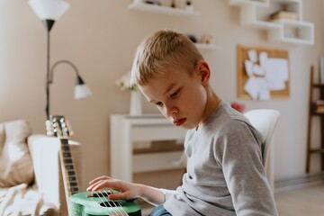 Mother and son playing guitar together, family love. The child wears a hearing aid, highlighting...