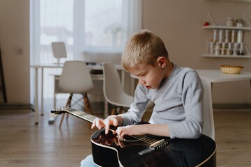 Mother and son playing guitar together, family love. The child wears a hearing aid, highlighting...