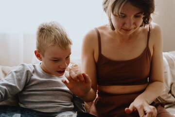 Mother and son playing guitar together, family love. The child wears a hearing aid, highlighting...