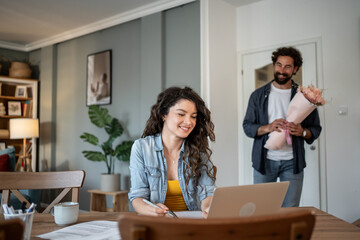 Fototapeta premium Woman working from home receiving flowers from husband