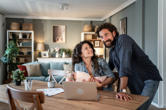 Happy couple receiving flowers during video call at home