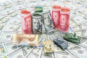 Economic conflict and diplomacy : Chinese yuan and US dollar bills rolled with miniature tanks represent the trade tension, financial battleground between the world's largest economies, US and China.