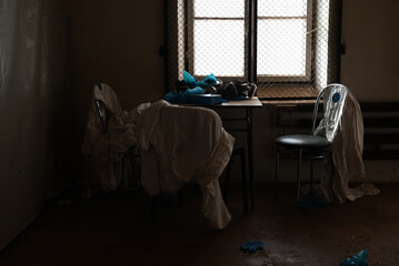 empty abandoned room with chairs, table, gas masks, and rubber gloves - illegal drug production concept