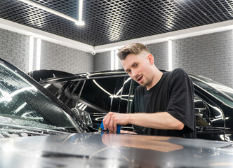 Car wrapping, detailing, tuning and styling. Detailer smoothes PPF. A car wrapping specialist...