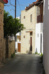 Steet in old Greek town. Traditional narrow street on Crete island. Stone buildings. Narrow greek street with stone walls and greek tree