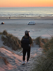 A traveler explores Denmarks picturesque beachfront as the sun sets, casting warm hues over the...