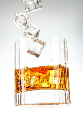 Hero shot of a whiskey glass with splashing ice cubes, showcasing the rich amber liquid and dynamic motion.