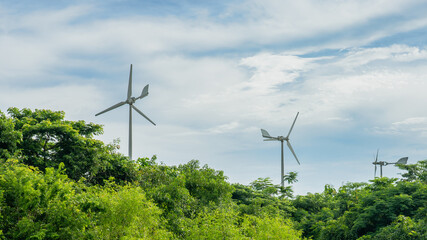 Three generating wind turbines are installed in the middle of nature with trees covered.