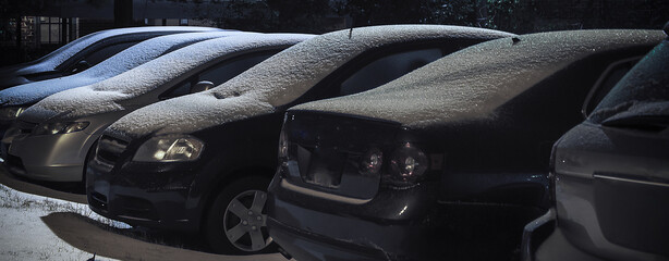 Close-up of several cars covered in light snow overnight.