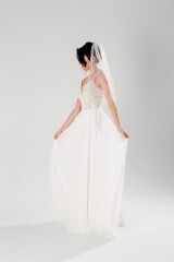 Bride in elegant white dress posing gracefully in a studio setting during a fashion shoot