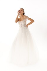 Elegant bride in a flowing white gown poses gracefully against a simple background during a...