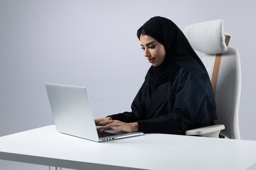 A collection of images of Arab business professionals, both male and female, in traditional clothing working together in a modern office setting, using laptops, discussing projects, and collaborating 