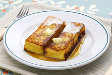 homemade french toast with butter, maple syrup and powdered sugar.