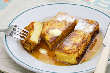 homemade french toast with butter, maple syrup and powdered sugar.