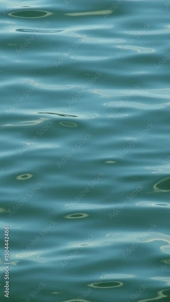Poster vertical footage of waves moving with calm ripples on the surface of a blue lake. abstract patterns 
