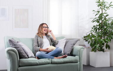 Obraz premium Young woman with smart glasses touching interface while holding popcorn