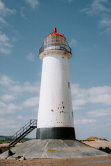 Tall white lighthouse under a clear blue sky on a sunny day.
