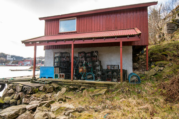 Fishing shack with stacked lobster traps by water.