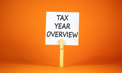 Tax year overview symbol. Concept words Tax year overview on beautiful white paper on clothespin. Beautiful orange background. Business tax year overview concept. Copy space.
