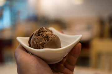 Chocolate ice cream in a white bowl on man hand