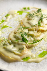 Closeup on portion of italian ravioli dumplings dish with creamy sauce