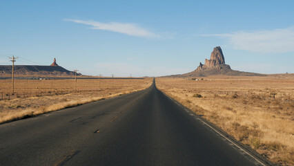 Driving on highway in hot dry desert area with amazing red rock formations Monument Valley park in Arizona United States. Pov from moving vehicle car riding downhill on asphalt road going to horizon