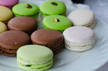 Assorted colorful macarons with chocolate, pistachio, and vanilla flavors arranged neatly on a...