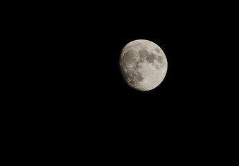 Obraz premium Detailed view of a waxing gibbous moon glowing against a dark night sky showcasing its craters and surface textures
