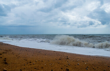 stormy coastal sea against the background of a cloudy sky covered with solid clouds