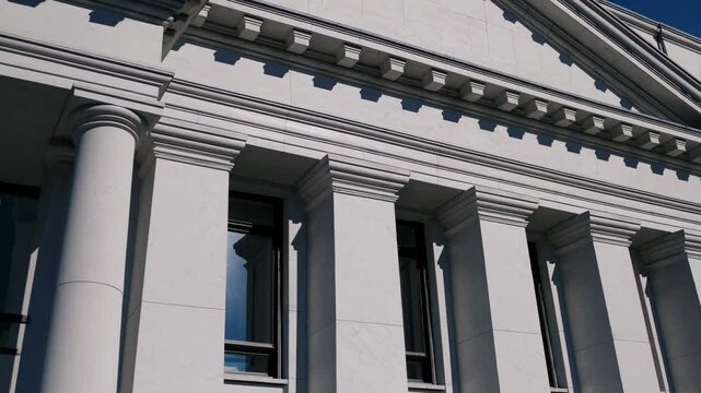 Classic architectural facade with white columns and decorative cornice under sunlight

