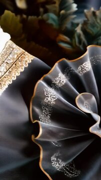 Elegant draped blue fabric with ornate silver pattern and gilded edging in a smooth textured flow