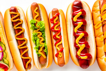 Hot dogs with mustard and ketchup resting on a white background