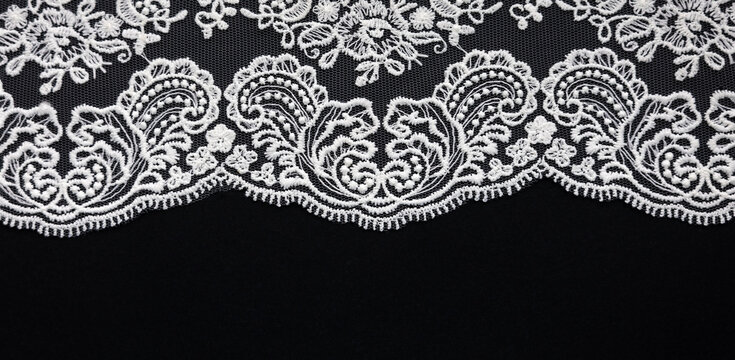 White lace close-up on black background. Texture banner. Selective focus and copy space