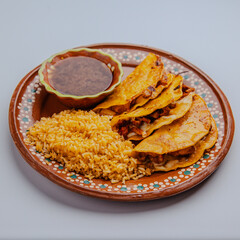 Authentic Mexican tostadas served with rice and consomm&eacute; on a traditional handmade clay plate. Vibrant street food isolated on a clean white background.