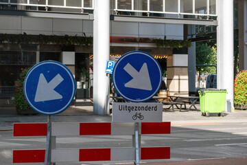 Street barricade and road detour sign, blur cafe bar tables, city center