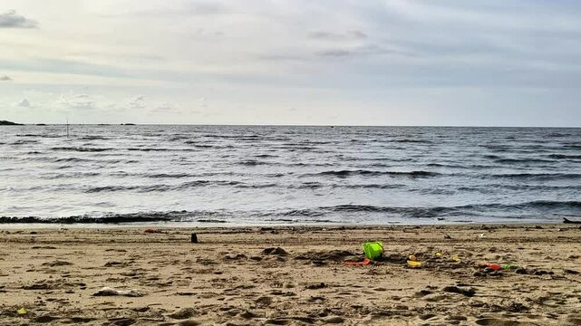 Sandy beach with gentle waves under cloudy sky
