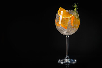 Aperol spritz cocktail in a glass with ice and orange on a black background