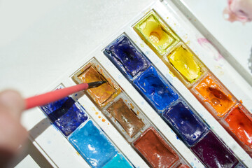 Colorful watercolor palette with bright pigments and brush creating artistic expressions.