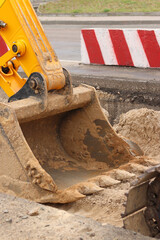 Close-up of excavator bucket. Excavator levels the ground on the site. Repair work in the city....