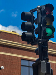 Green Traffic Light Against Urban Brick Building and Blue Sky