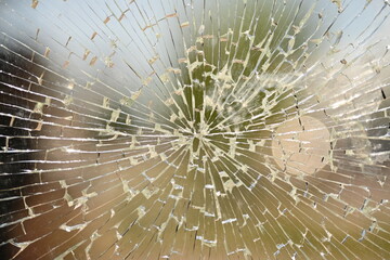 shattered safety glass on a public transport bus stop. The cracks form a circular spiderweb...