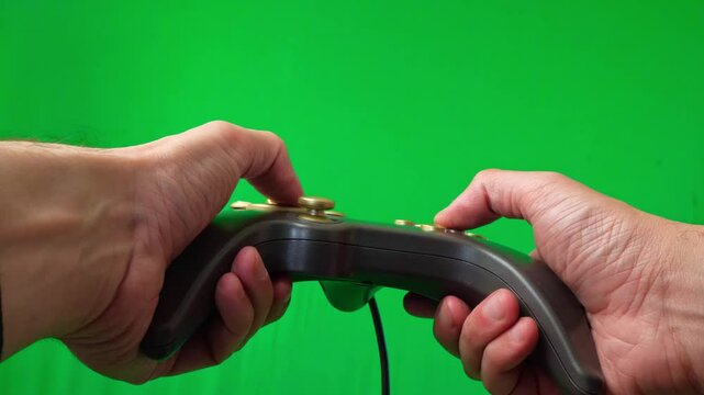 A close-up shot of a hand holding a white wireless controller against a vibrant green screen background. The thumb is positioned over the left joystick, suggesting active gameplay
